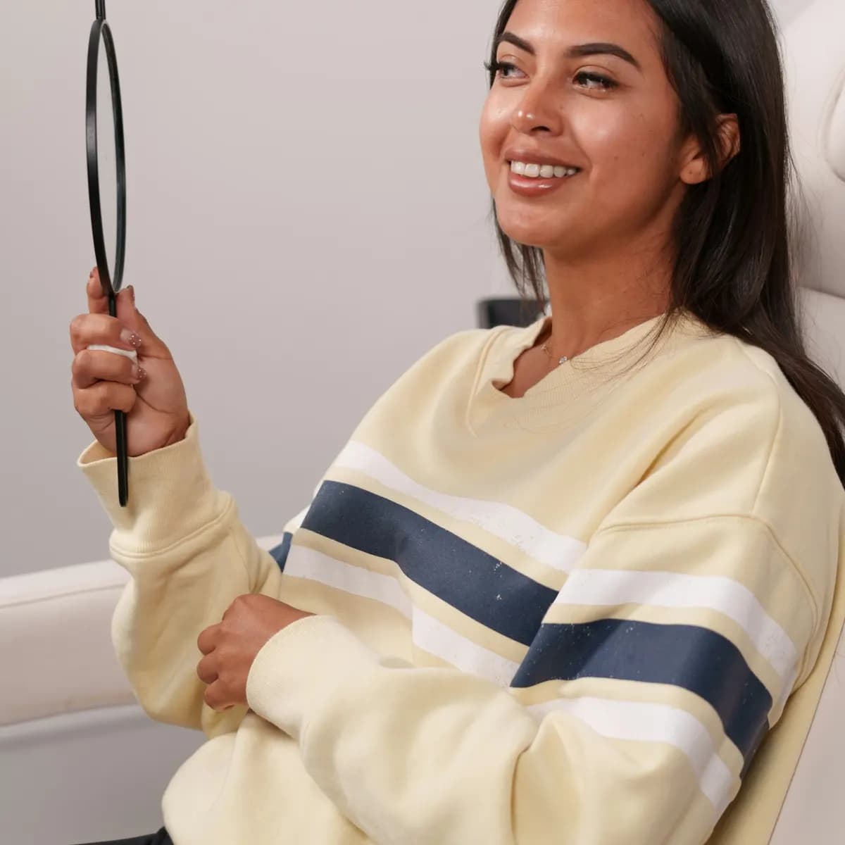 Paciente sonriendo mientras mira su piel en un espejo de mano